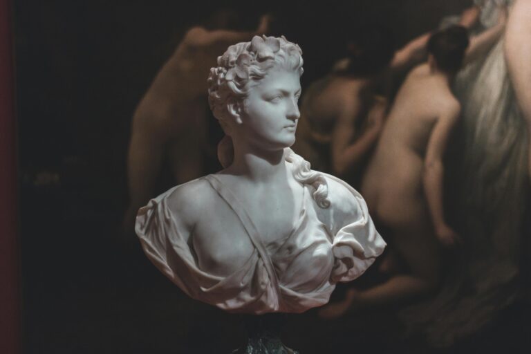 A marble bust sculpture displayed in a dimly lit, classic art gallery.